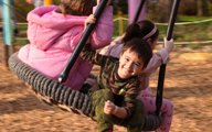 3 kids playing on a bucket swing