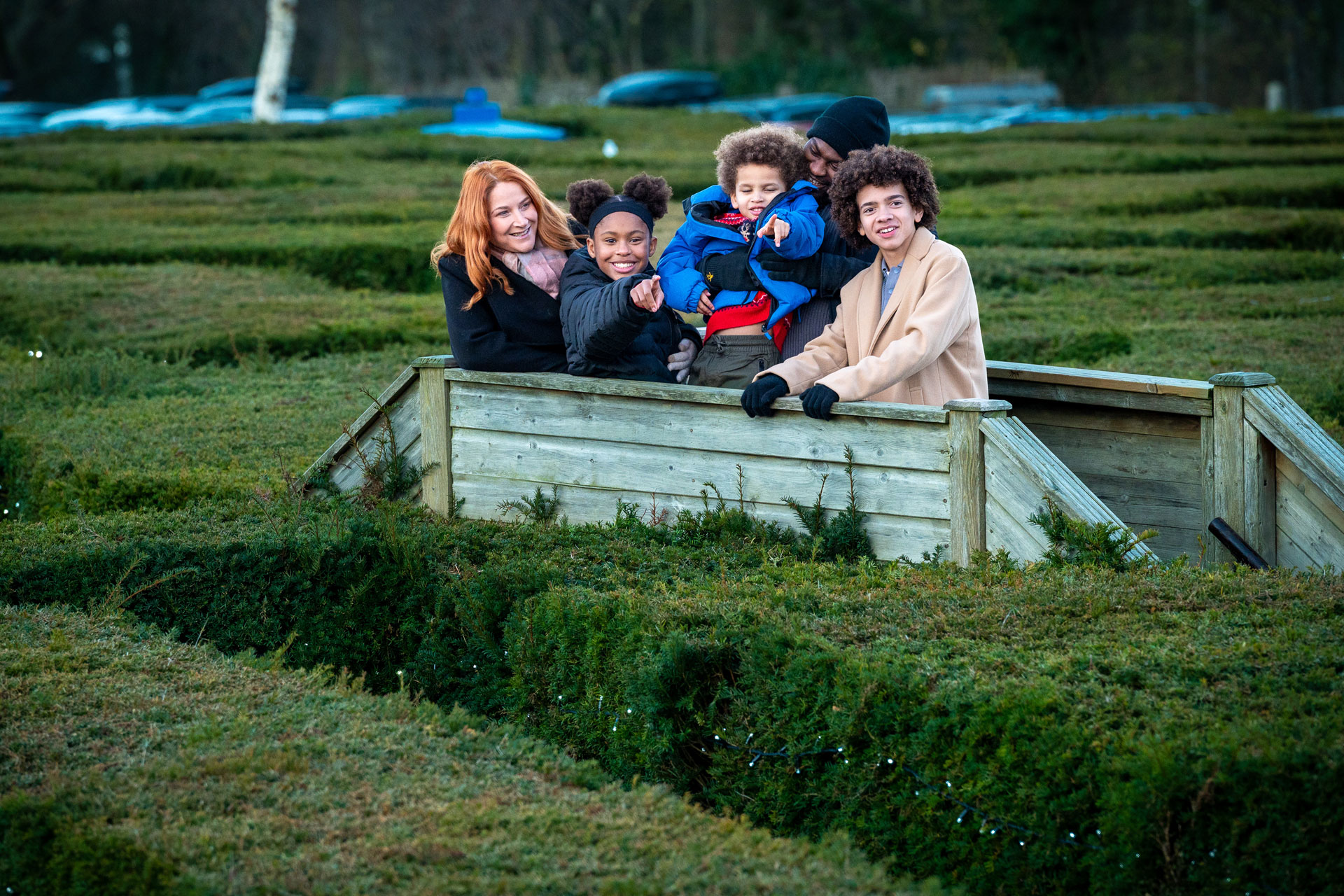 family on a bridge in the middle of a maze pointing at object in distance