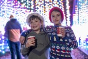 Two children smiling with hot chocolates infront of the illuminations