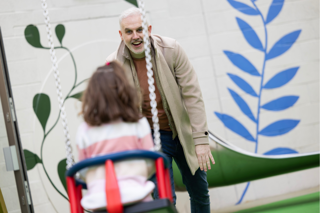 A smiling man pushes a young girl on a swing inside Stockeld Park’s indoor play area.