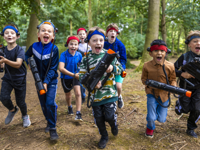 group of boys running with laser guns in wooded arena