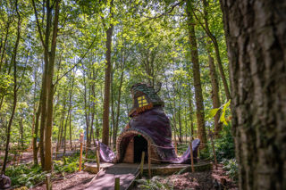 magical house in the shape of a purple witches hat in a forest