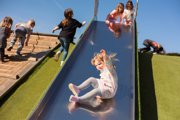 A young girl sliding down farmer fosters slide