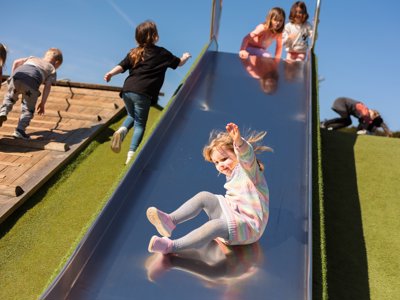 A young girl sliding down farmer fosters slide