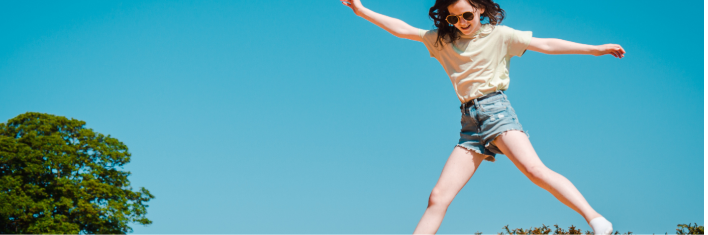 A young girl jumping in the air with a blue skyline in the background.