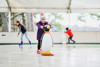A young girl ice skating with a penguin skating aid