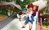 3 kids sliding down the big spider slide in spider's lair
