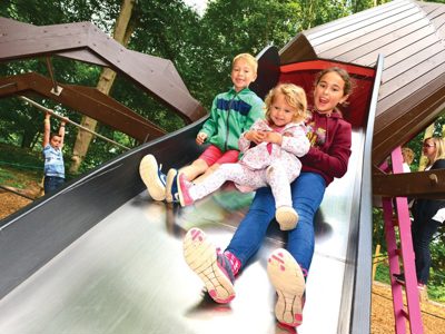 3 kids sliding down the big spider slide in spider's lair