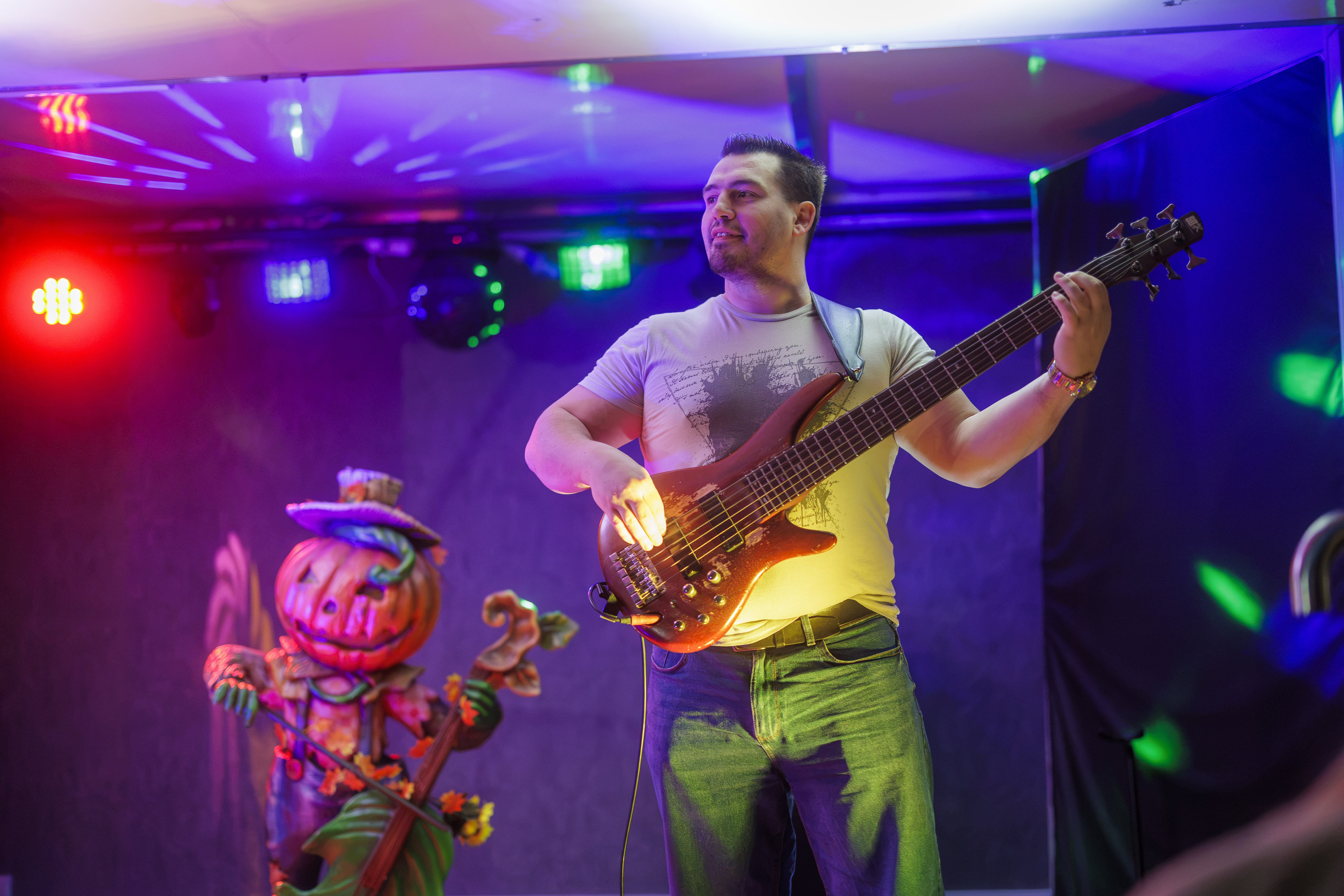 Man Playing Bass On Stage With Pumpkin Decoration