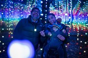 Family of three smiling in the tendrills while looking at the lights
