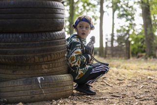 boy in camo crouching behind tyres with a laser gun