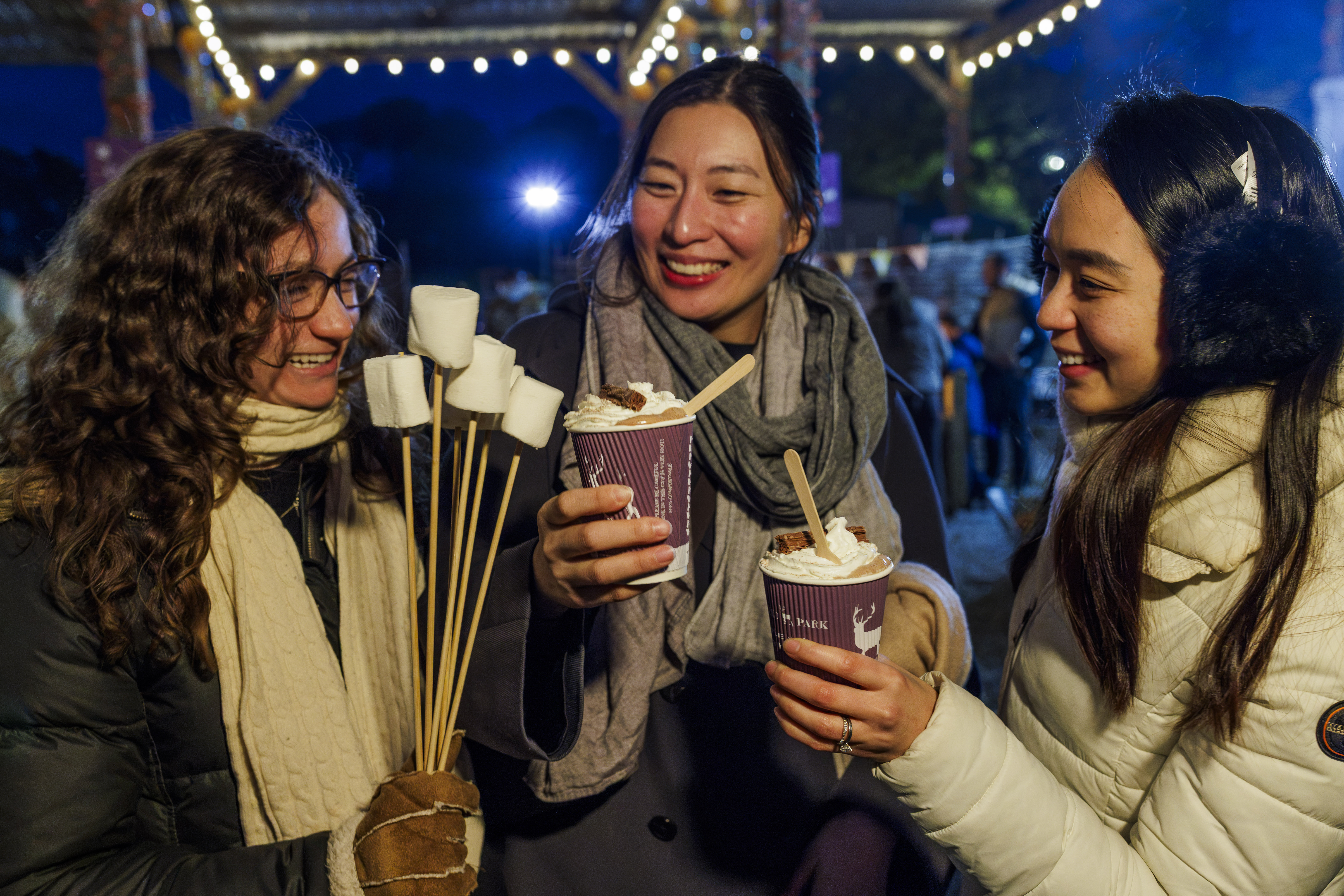 Three Guests Holding Hot Drinks And Marshmallows