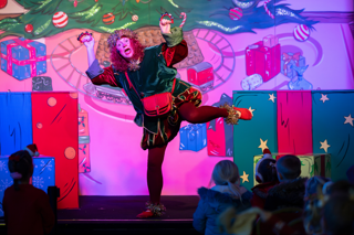 Alt text: Woman dressed in an Elf costume performing in a panto in Stockeld Park’s theatre. 