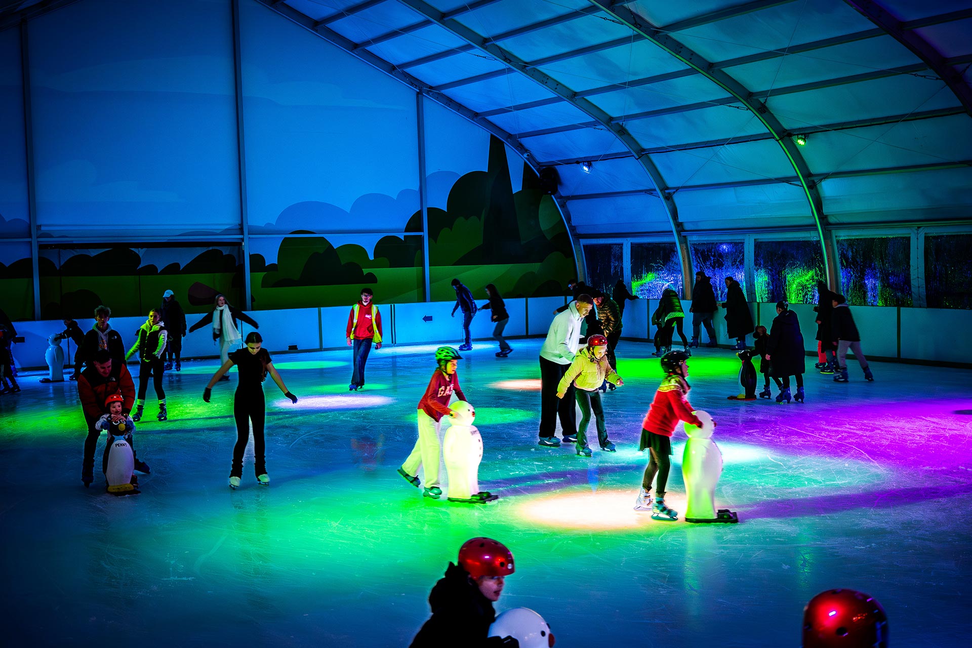overview of ice rink at night with skaters and coloured lights