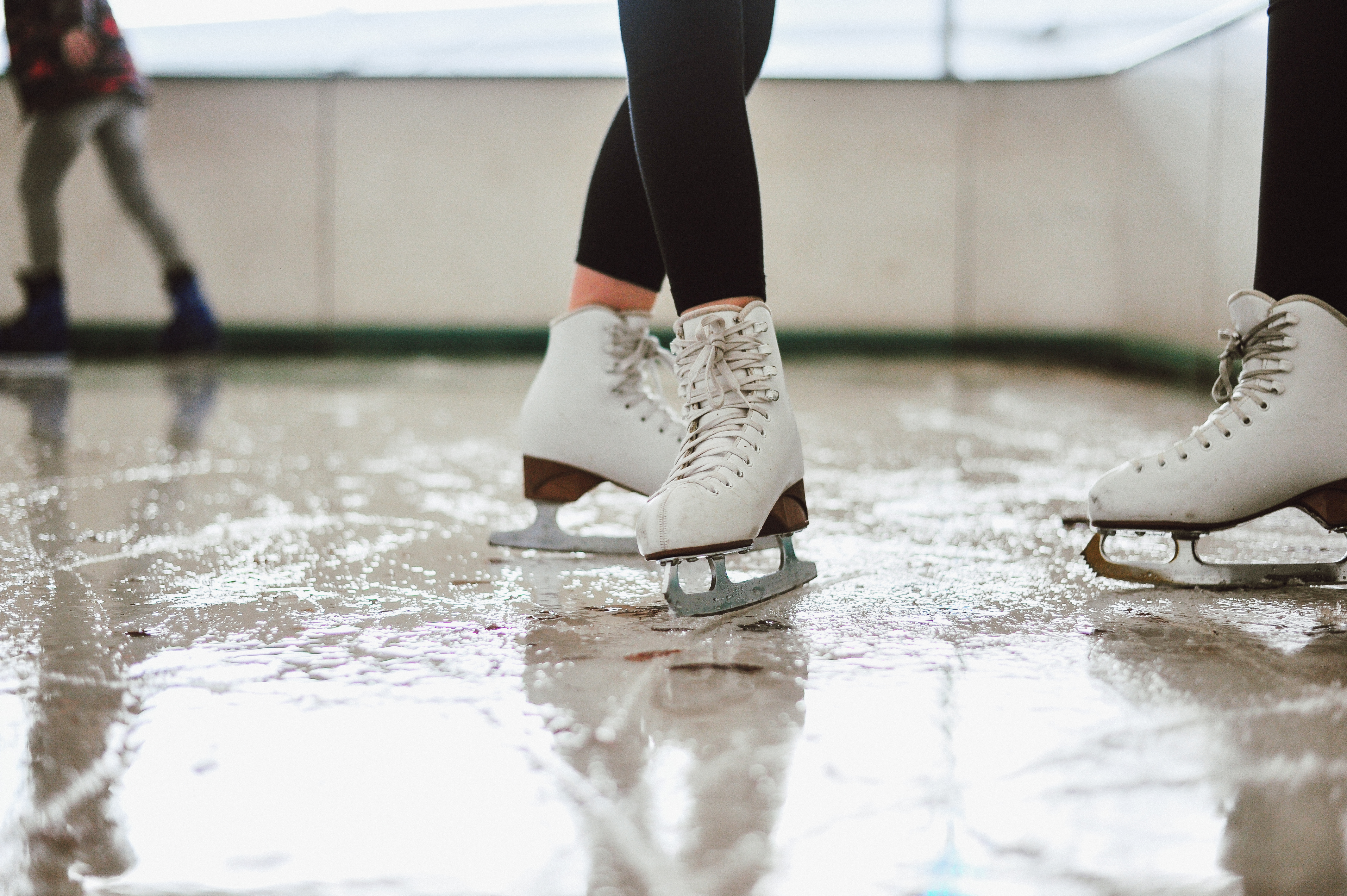 close up pair of white ice skates on an outdoor rink