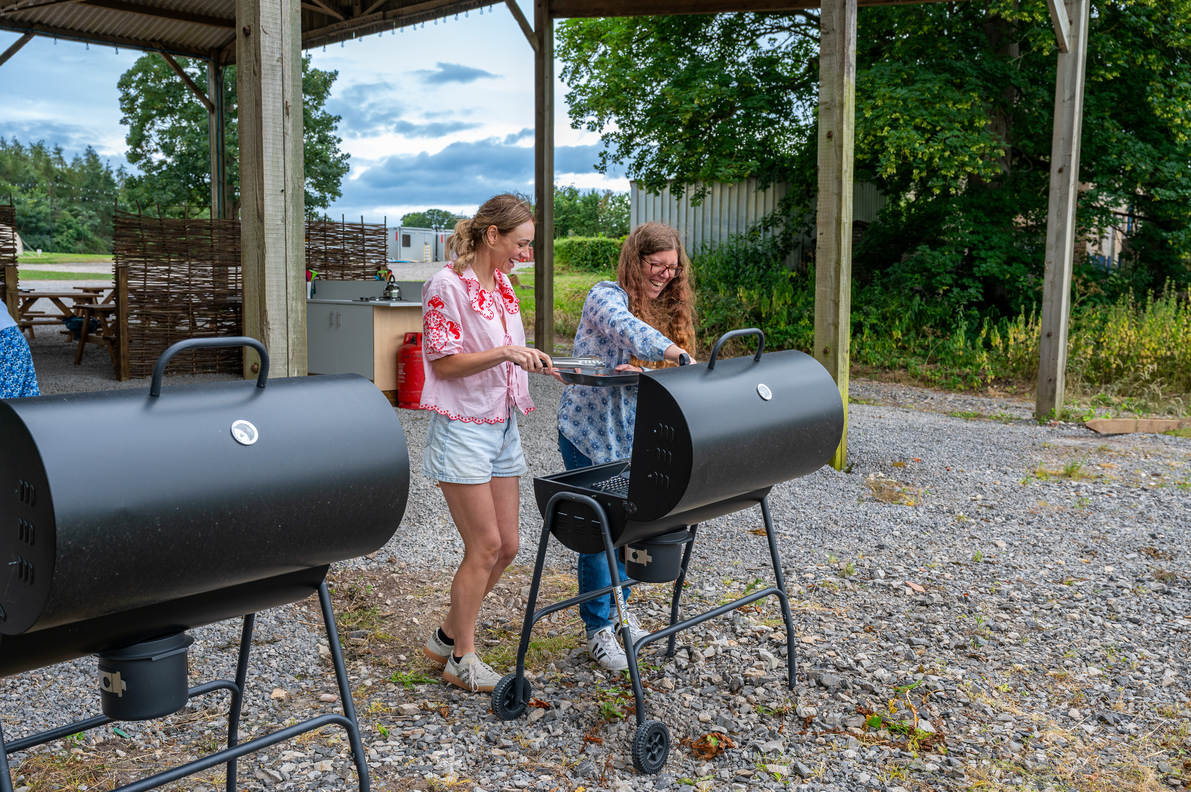 Two Women Cooking Food On A Barbecue On A Campsite