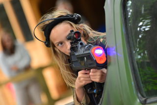 girl with blonde hair aiming laser gun in laser tag