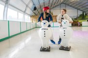 young girls ice skating with snowmen skating aids