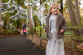 little girl wearing ghost bride halloween costume under an arch with cobwebs