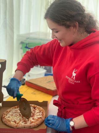 A staff member cutting a pizza