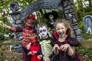 four children in a spooky forest in halloween costumes in front of cemetery