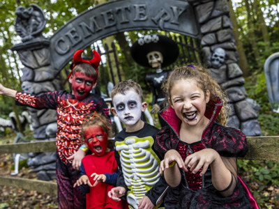 four children in a spooky forest in halloween costumes in front of cemetery