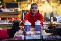 barista in red hoodie passing two hot chocolates with whipped cream to guests