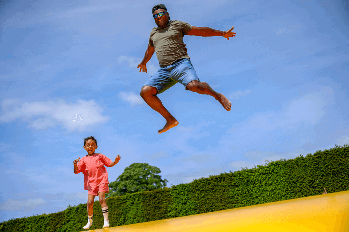 Man and daughter bouncing on the giant pillow