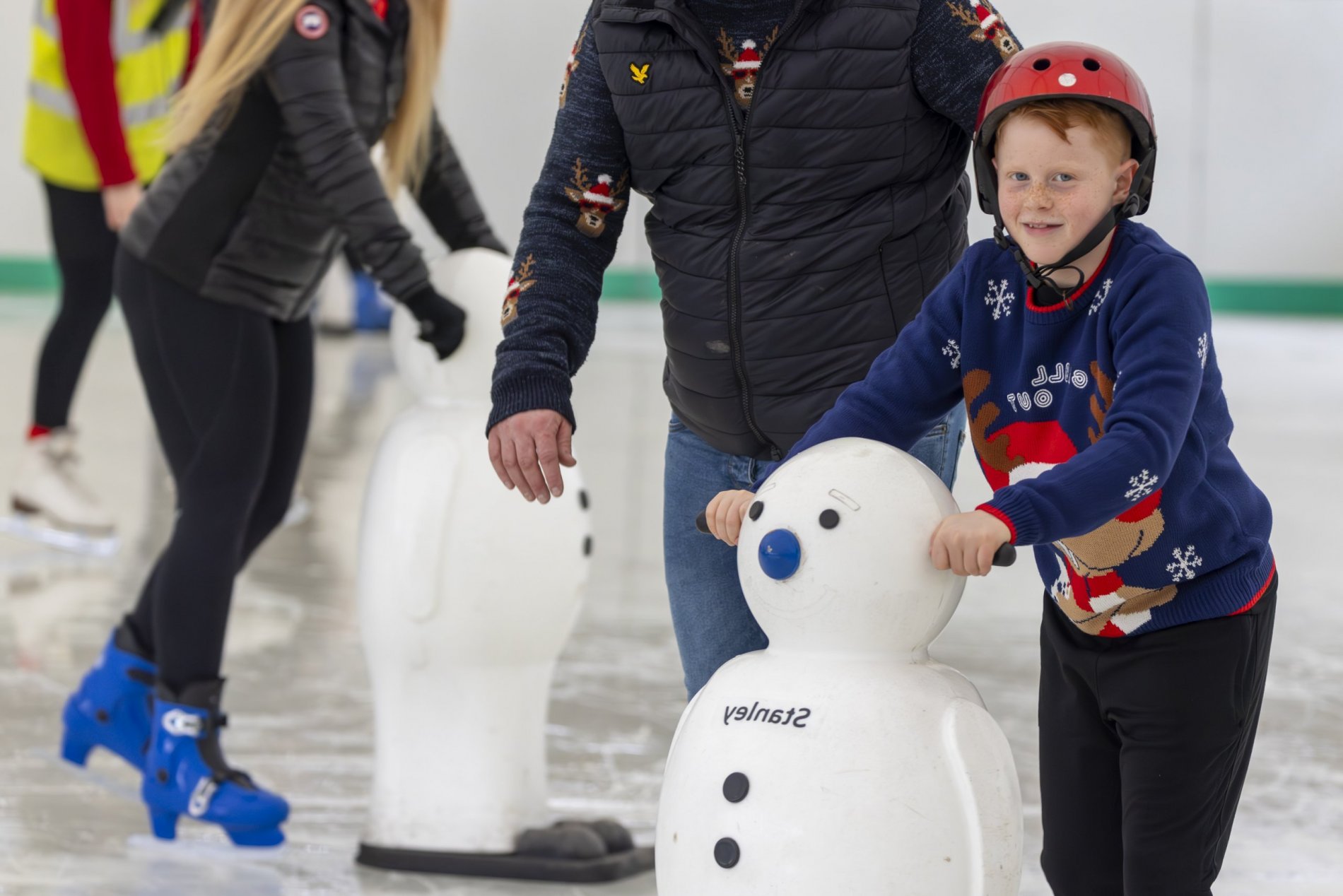 A young boy learning to ice skate with a skating aid