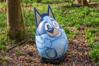 giant easter egg painted as blue dog in forest