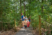 boy running down path in forest with family behind