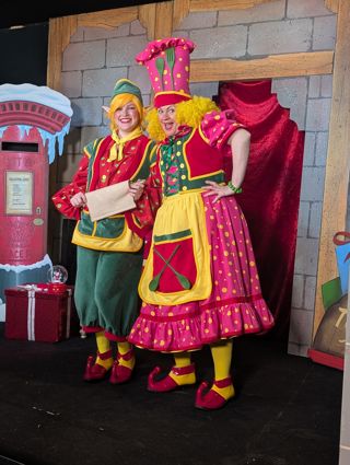 2 elves smiling on stage with a scroll