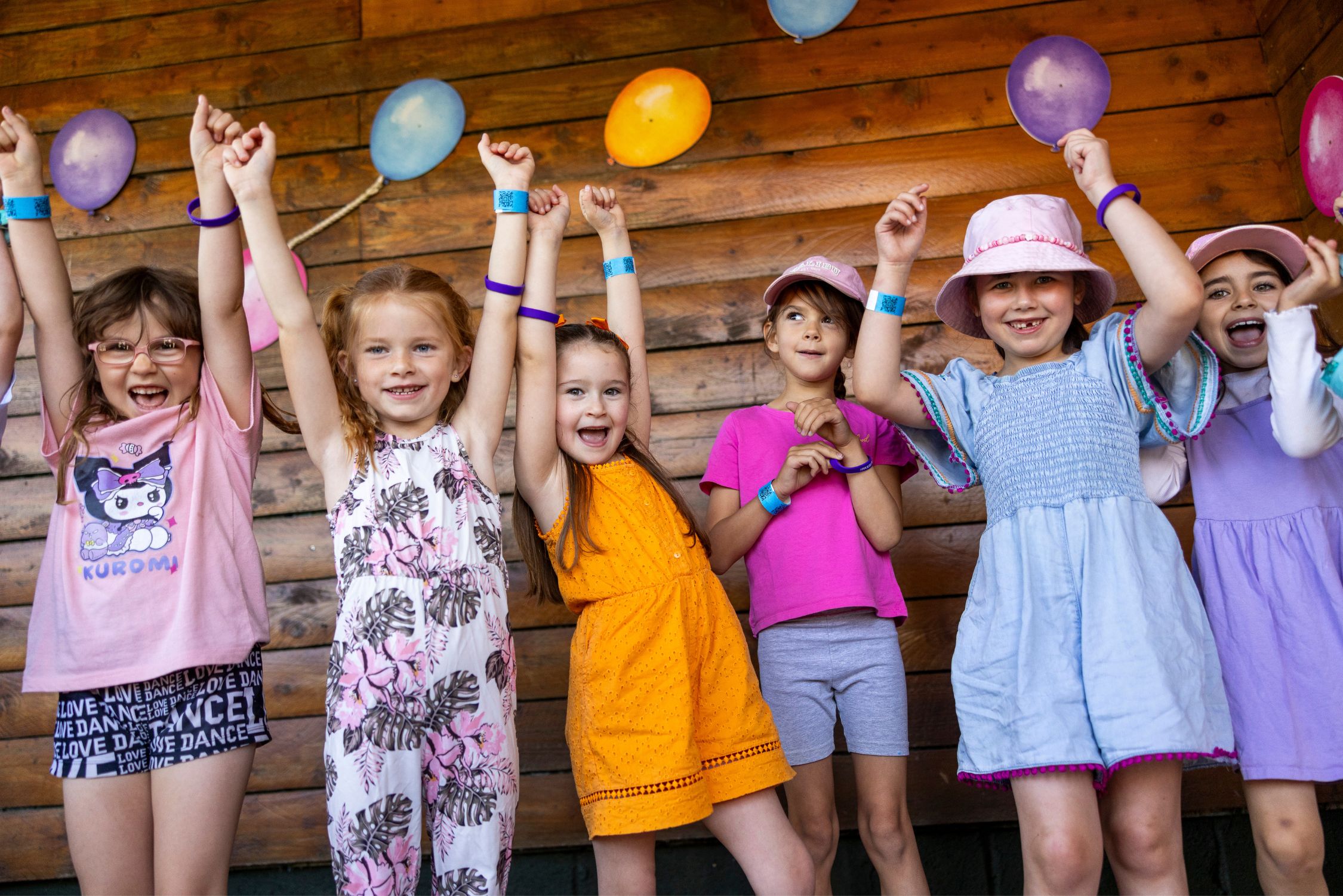 A group of girls celebrate in front of balloons.