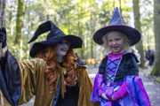 woman dressed as witch smiles at a little girl in halloween witch costume