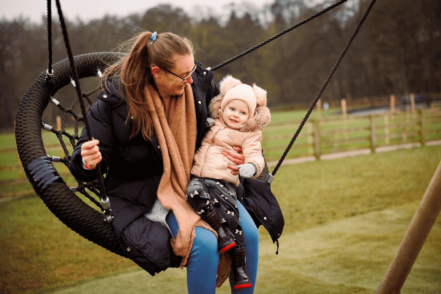Family playing on swing in Stockeld Park's outdoor playground
